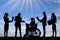 Silhouette of a disabled woman in a wheelchair and his work team