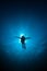 Silhouette diver sunrays behind at Underwater blue background i