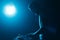 Silhouette of DJ mixing vinyl records on party in night club. Disc jockey playing techno music set in bright blue stage lights