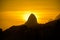 Silhouette of Dois Irmaos Mountain on the background of gold sun
