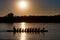 Silhouette of a Dragon boat with paddling people at sunset on Da
