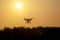 Silhouette drone against the background of the sunset. Flying drones in the evening sky.