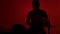 Silhouette drummer playing drum on a red background. Studio shot footage