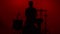 Silhouette drummer playing drum on a red background. Studio shot footage