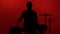 Silhouette drummer playing drum on a red background. Studio shot footage