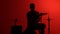 Silhouette drummer playing drum on a red background. Studio shot footage