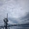 silhouette of electric pole with messy wires photographed on an overcast day from below