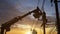 Silhouette electrician working on poles to install high-voltage