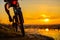 Silhouette of Enduro Cyclist Riding the Mountain Bike on the Rocky Trail at Sunset. Active Lifestyle Concept. Space for Text.