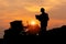 Silhouette of Engineer foreman at construction site, Road construction worker and road grader tractor with blurred sunset