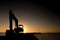 Silhouette of Excavator loader at the sunset beach behind