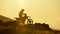 Silhouette of Extreme Pro Motocross Biker riding motor bike opposite sunset