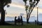 Silhouette of family enjoying sunset at park with bicycle parked beside lamp post.