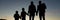 Silhouette of a family of five standing under the evening sky