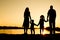 Silhouette family, including his father, mother and two children in the hands of