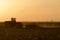 Silhouette of farmer tilling his land after the harvest.