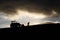 Silhouette of farmer with tractor working and digging high up in the clouds