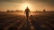 Silhouette of a farmer walking through a field at sunset