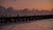 Silhouette of Fast Moving People Walking on Long Pier over Twilight Sky; Dark Sea Frozen in Time