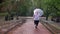 Silhouette of fat ginger girl is walking in park under rain, holding umbrella, weather concept, back view