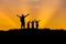 Silhouette father and children standing raised hands up on sunset