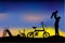 Silhouette of father have fun with his children, slide, tricycle and folding bike at park when sunset or sunrise