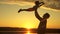 Silhouette of father and healthy child flying over sun. Dad tosses his happy little daughter in air on beach, having fun