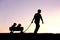 Silhouette of Father Pulling Sons in Wagon at Sunset