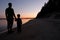 Silhouette of father and son holding hands, standing on the beach at sunset. Family on vacation. Calm water, tranquil weather,