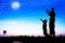 Silhouette of father use hand point his son look at full moon