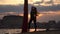 Silhouette of Female dancer showing her flexibility and splits with red aerial silk on the cityscape background during