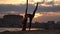 Silhouette of Female dancer showing her flexibility and splits with red aerial silk on the cityscape background during