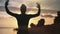 Silhouette of female jumping raising hand enjoying workout at sunset beach. 4k Dragon RED camera
