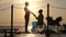 Silhouette of female and male handicapped on wheel chair holding arms and look at horizon in sea