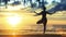 Silhouette female practicing yoga on the beach at magnificent sunset.