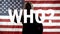 Silhouette of a female speaker talking and gesticulating against the background of the American flag.