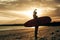 silhouette of female surfer posing with surfboard at sunset