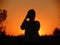 Silhouette of a female tourist taking photos of a sunset in a desert