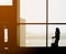 Silhouette of female traveler making phone call in front of jet bridge in airport`s departing gate.