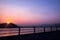 Silhouette of fence, mountain, ocean and sun at sunset