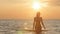 Silhouette figure of a woman coming out from the water in a swimsuit at dawn, a girl swimming in the sea enjoying sunrise, the con