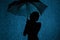 Silhouette of the figure of a young girl with an umbrella in the rain