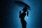 Silhouette of the figure of a young girl with an umbrella in the rain