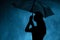 Silhouette of the figure of a young girl with an umbrella in the rain, a young woman is happy to drops of water, concept weather