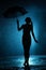 Silhouette of the figure of a young girl with an umbrella in the rain, a young woman is happy to drops of water, concept weather