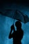 Silhouette of the figure of a young girl with an umbrella in the rain, a young woman is happy to drops of water, concept weather