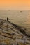 Silhouette of a fisherman with boat passing by during sunset