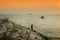 Silhouette of a fisherman with boat passing by during sunset