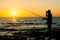 Silhouette of a fisherman fishing in sunset time on the open sea.