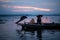 Silhouette of fisherman at sunrise, Standing aboard a rowing boat and casting a net to catch fish